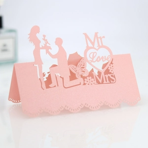 Detail of pink laser-cut wedding place card with romantic silhouette and butterfly design