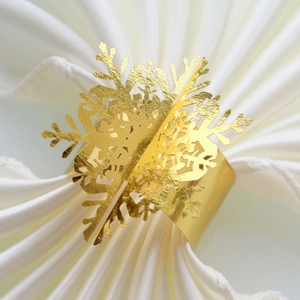 Golden snowflake napkin ring with elegant cutout design on a white fabric background