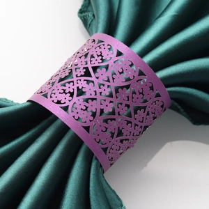 Macro detail of laser-cut purple floral lace napkin ring on green satin fabric