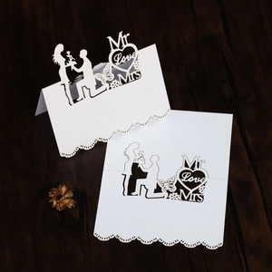 Laser-cut white wedding place card with Mr and Mrs heart silhouette on wood