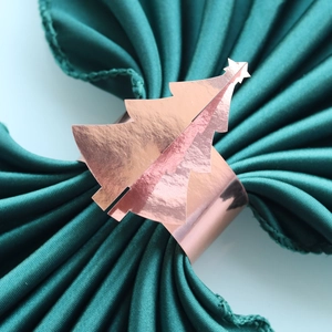 Macro d'un rond de serviette sapin de Noël en or rose sur tissu vert foncé élégant