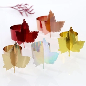 Detail view of five metallic maple leaf napkin rings in red, gold, and rose gold colors