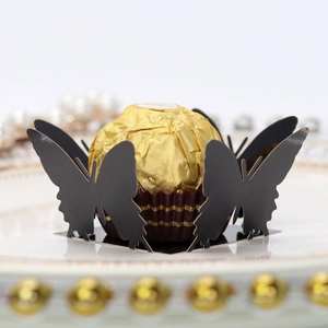 Detail showing black laser-cut butterfly cupcake wrapper with gold chocolate accent