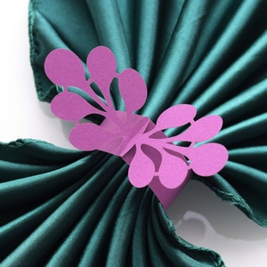 Detailed laser-cut purple pearl paper napkin ring with intricate leaf pattern on satin