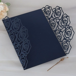 Detail of navy blue laser-cut rose pattern on wedding invitation card with cardstock texture