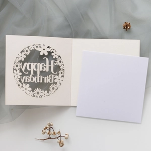 Détail d'une carte d'anniversaire découpée au laser avec motifs floraux et feuillet