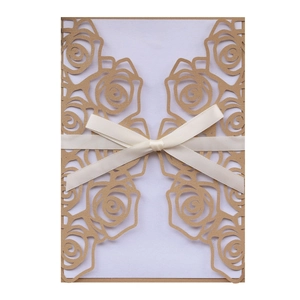 Detail of laser-cut rose patterns on elegant wedding invitation with ribbon bow