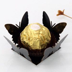 Macro view of laser-cut black butterfly cupcake wrapper with intricate hollow lace detail