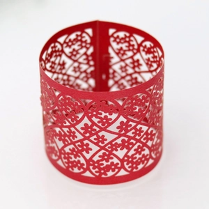 Close-up of laser-cut red paper napkin ring with floral hollow lace patterns