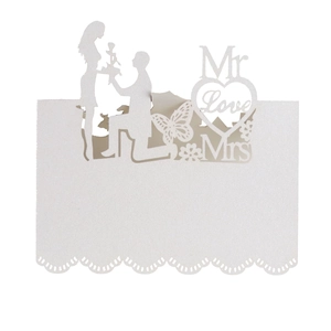 Close-up of laser-cut butterfly and heart details on white pearlescent wedding place cards