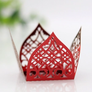Detail of red laser-cut cupcake wrapper featuring intricate lace floral patterns and crown shape