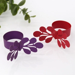 Detailed laser-cut paper napkin rings in purple and red with elegant leaf design