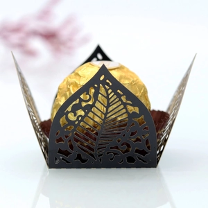 Detail of laser-cut black leaf hollow candy box with gold foil chocolate inside