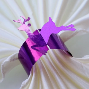 Close-up of a purple laser reindeer napkin ring on a white satin fabric for Christmas