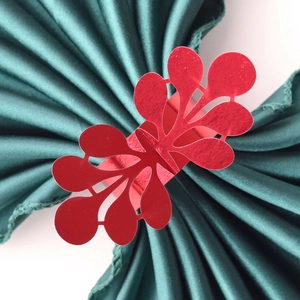 Macro detail of laser-cut red paper napkin ring with floral pattern on green satin