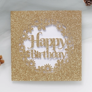 Gros plan d'une carte Happy Birthday dorée à paillettes avec des motifs de marguerites