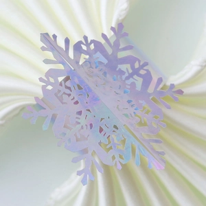 Macro shot of laser-cut iridescent snowflake napkin ring with holographic festive shine