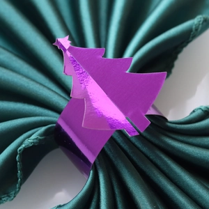 Détail macro du rond de serviette sapin de Noël violet sur tissu satiné vert