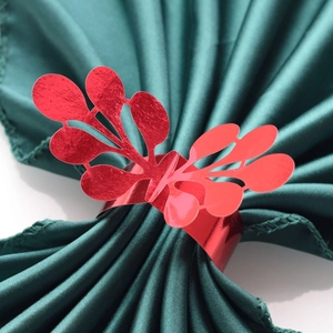 Red metallic leaf napkin ring with hollow design on deep green satin cloth