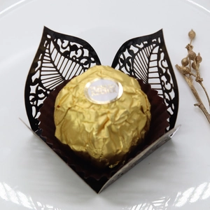 Macro shot of laser-cut black hollow leaf chocolate liner with elegant gold accents