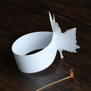 Macro shot of white laser-cut leaf napkin rings showing detailed hollowed paper patterns