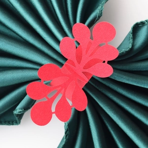 Detail of red laser-cut wedding napkin ring with intricate lace pattern on green silk
