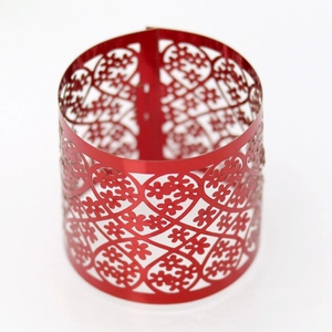 Detailed macro view of laser-cut red metallic napkin ring with intricate floral patterns
