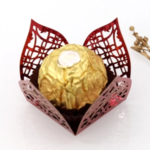 Macro detail of laser-cut wedding candy box with intricate red hollow pattern and shimmer