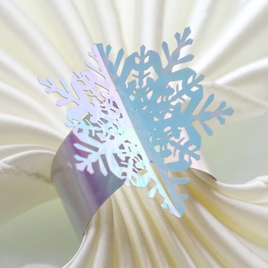 Macro shot of laser-cut iridescent snowflake napkin ring with detailed texture on white fabric