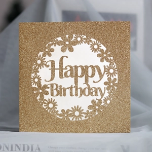 Détail de la carte Happy Birthday en paillettes dorées avec motifs de marguerites découpés