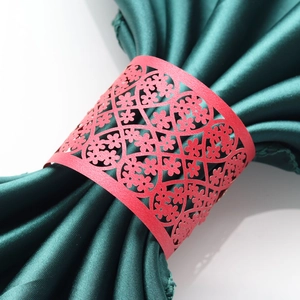 Macro detail of red pearlescent paper napkin ring with intricate floral laser-cut pattern