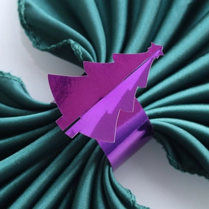 Gros plan d'un rond de serviette sapin de Noël violet miroir sur tissu vert foncé