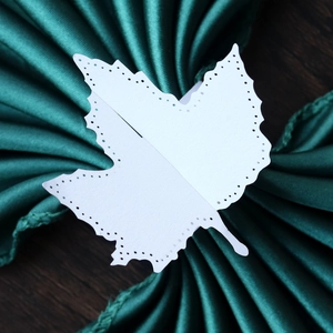 Detailed view of laser-cut white maple leaf paper napkin ring with decorative hollow dots
