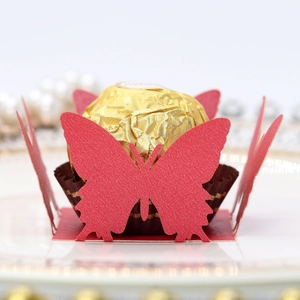 Detail of laser-cut red butterfly chocolate box on a white porcelain gold-rimmed plate