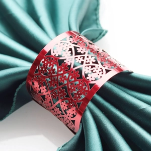 Macro detail of red laser-cut plum blossom napkin ring on silk napkin