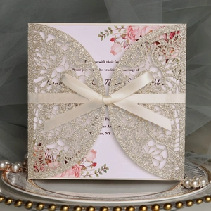 Detail der lasergeschnittenen Hochzeitskarte mit weißer Satinschleife und Blumenmuster