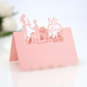 Macro detail of laser-cut pink pearlescent paper wedding place card with love patterns