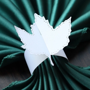 Detail of white laser-cut maple leaf paper napkin ring for elegant wedding table settings