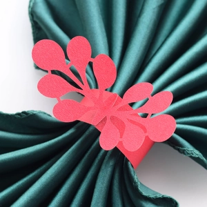 Detailed laser-cut paper napkin ring with pink lace pattern on green satin cloth