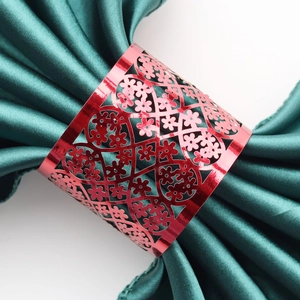 Close-up of red hollowed-out metal napkin ring with laser-cut lace floral pattern
