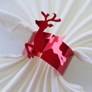 Detail of a shiny red reindeer paper napkin ring on a white napkin for Christmas