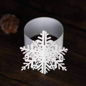 Macro detail of laser-cut white snowflake paper napkin ring on a dark wooden background