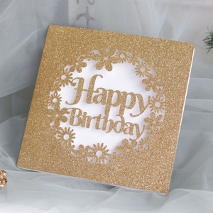 Détail macro de la carte pailletée dorée avec couronne de marguerites découpée au laser