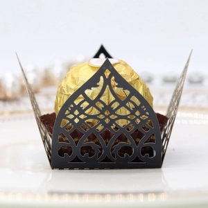 Close-up of laser-cut black lace chocolate wrapper on an elegant white porcelain plate