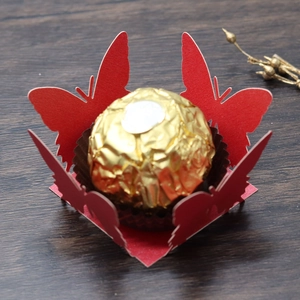 Detailed laser-cut red butterfly paper candy holder with a golden chocolate ball inside