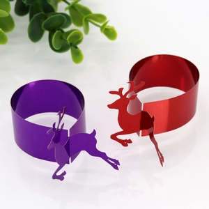 Detail of glossy metallic paper napkin rings with cutout reindeer for festive table setting