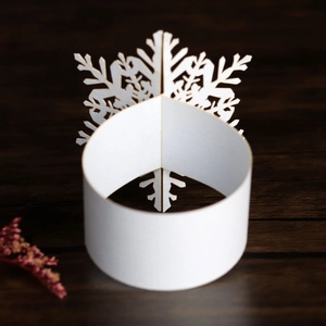 Close-up of laser-cut white pearl paper snowflake napkin rings on a wooden surface