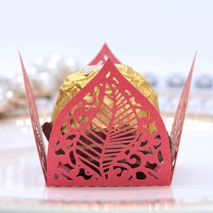 Macro view of red laser-cut leaf pattern candy wrapper with gold chocolate decorative holder