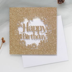 Gros plan d'une carte d'anniversaire pailletée découpée au laser avec motif floral et enveloppe
