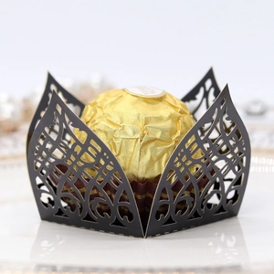 Detail of laser-cut hollow vine pattern on black paper candy box with gold chocolate